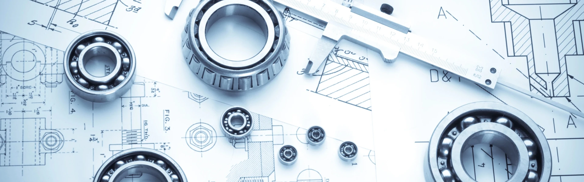 Plan technique de différentes pièces sur lequel sont posés des outils de mesure et pièces métalliques